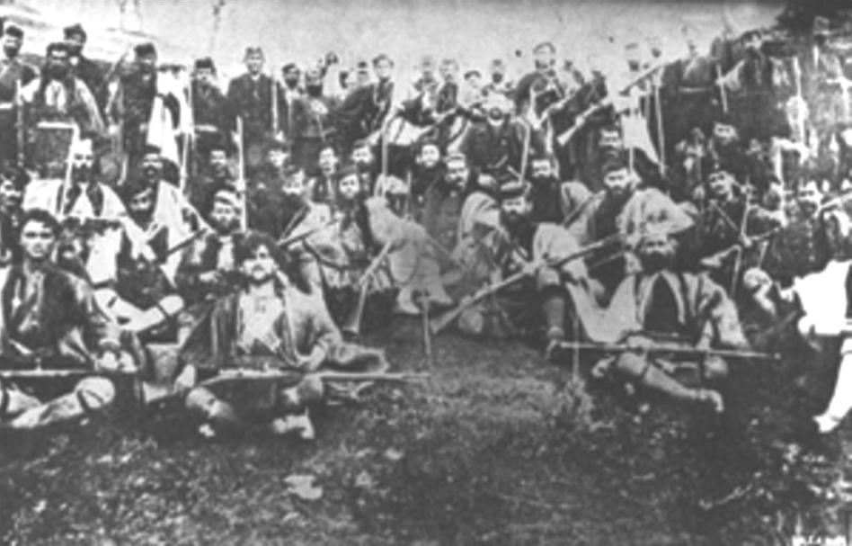 Ο Αντώνιος Βλαχάκης με τους άντρες τού ένοπλου σώματός του. Διακρίνεται καθισμένος στο κέντρο τής φωτογραφίας, σε πρώτο πλάνο. Ακριβώς αριστερά του εικονίζεται ο Λουκάς Κόκκινος με την φουστανέλα.